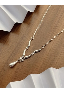Macro detail of S925 sterling silver waterdrop pendant necklace on dark wood background