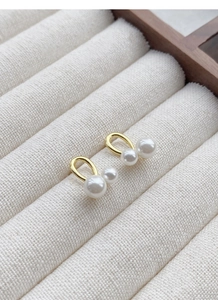 Détail de boucles d'oreilles clous croisées en argent S999 plaqué or avec perles lisses