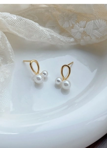 Vue détaillée de boucles d'oreilles en argent S999 doré avec d'élégantes perles blanches