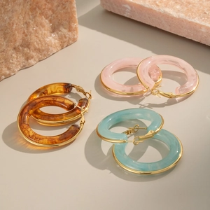 Detailed view of three pairs of resin and gold metal hoop earrings in assorted colors