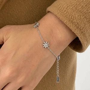 Detail of adjustable stainless steel daisy bracelet with floral charms on a wrist