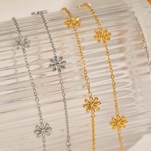 Macro detail of gold and silver dainty daisy chain bracelets on textured glass