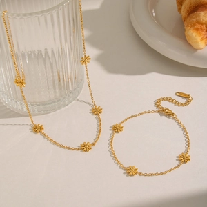 Detail of gold daisy jewelry set with necklace and bracelet in high-quality stainless steel