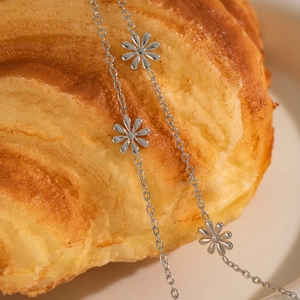 Detailed close-up of a silver daisy charm necklace draped over a pastry background