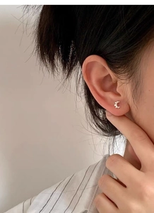 Macro view of minimalist S925 sterling silver textured stud earring on ear