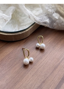 Gros plan détaillé de boucles d'oreilles croisées dorées avec perles sur fond de dentelle