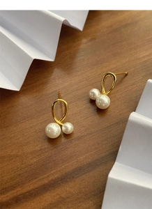 Détail des boucles d'oreilles dorées avec perles brillantes sur fond bois sombre