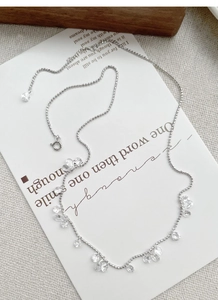 Détail d'un collier en argent S925 avec zircons en goutte d'eau sur papier d'art