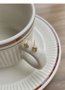 Gros plan de boucles d'oreilles roses dorées sur le bord d'une tasse à café rétro blanche