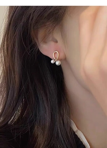Gros plan de boucles d'oreilles élégantes en perles dorées portées par un mannequin