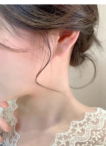 Gros plan d'une petite boucle d'oreille rose dorée portée sur le lobe de l'oreille