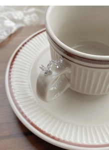 Macro de boucles d'oreilles papillon en argent avec cristaux sur une tasse en céramique