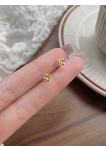 Gros plan de boucles d'oreilles roses dorées tenues à la main sur dentelle chic