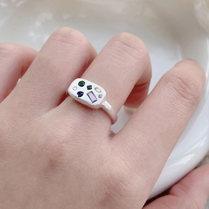 Matte S925 sterling silver ring with colorful zircons on a white ceramic background