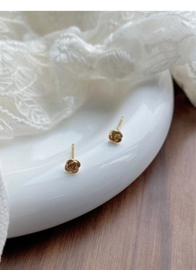 Vue macro de boucles d'oreilles roses en relief doré sur un plateau en céramique blanc