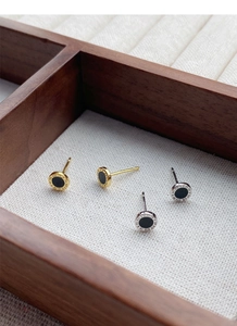 Close-up of S999 silver earrings with Roman numerals and black inlay on a wooden tray