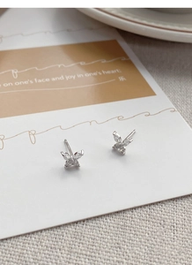 Détail de boucles d'oreilles papillon en argent avec pavé de zircons sur fond de tissu