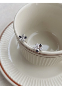 Detail of sparkling cherry blossom stud earrings with pavé crystals on a ceramic cup