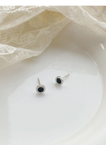 Macro detail of silver Roman numeral earrings with black inlay on a lace background