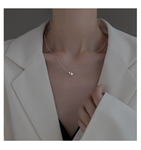 Detail shot of a sterling silver star pendant necklace on a neck with a white blazer