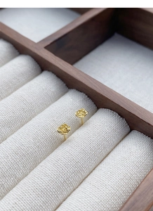 Vue détaillée de boucles d'oreilles rose dorée sur un support en bois et lin