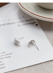 Gros plan de boucles d'oreilles croissants en argent avec finition mate brossée sur carte