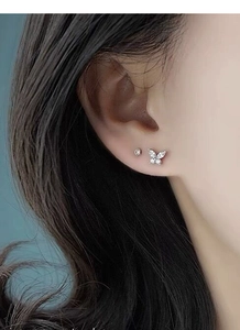 Gros plan de boucles d'oreilles papillon en argent massif S999 avec zircon sur oreille