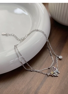 Détail macro du bracelet double couche en argent avec un pendentif papillon multicolore