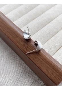 Détail de boucles d'oreilles en argent S999 montrant la texture brossée et le poinçon S925
