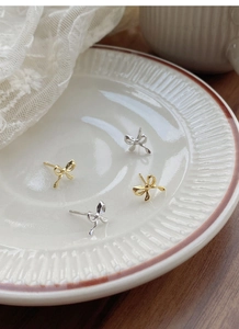 Macro shot of S925 sterling silver bow earrings in gold and silver finish with hallmark