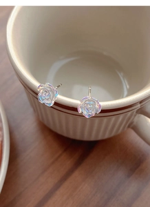 Detailed view of camellia stud earrings featuring iridescent resin petals on a ceramic cup