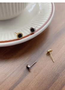 Detail view of silver and gold Roman numeral stud earrings with black inlay inserts