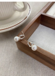Detailed macro view of S925 silver irregular geometric earrings with round white pearls