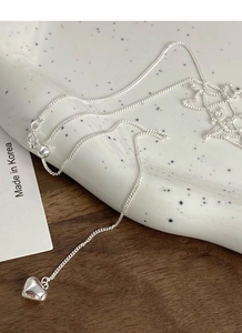 Detailed macro of S925 sterling silver heart pendant on O-chain over white porcelain