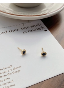 Macro detail of gold S999 silver earrings with Roman numerals and black inlay center