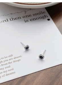 Macro shot of S925 silver stud earrings with black inlay and Roman numeral engravings