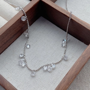 Collier en argent S925 avec pendentifs en zircon goutte et rond sur un tissu texturé