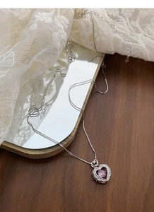 Macro detail of S925 sterling silver heart necklace with pink stone and zircon on lace