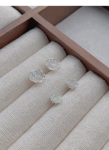 Detailed macro view of S925 silver iridescent flower earrings on a velvet display