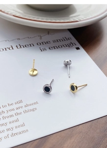 Close-up of gold and silver stud earrings with Roman numerals and black inlay