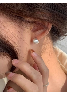 Gros plan sur des boucles d'oreilles minimalistes en argent mat avec une texture brossée