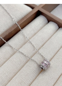 Macro shot of silver cylinder pendant featuring pink square diamonds and white pavé stones