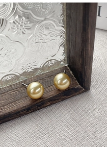 Detailed view of luxury golden pearl earrings on vintage wood and glass background
