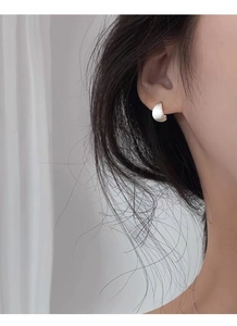 Gros plan de boucles d'oreilles élégantes en argent mat portées par un mannequin de profil