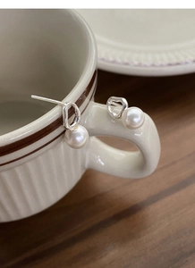 Detailed macro view of S925 silver irregular geometric pearl earrings on a cup