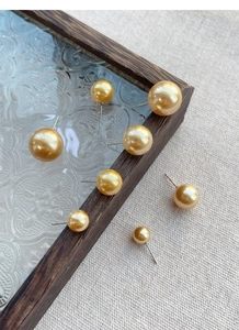 Detailed view of champagne gold pearl earrings in multiple sizes on textured glass