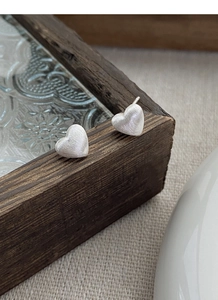 Vue macro de boucles d'oreilles cœur en argent S999 avec texture métal brossé mat