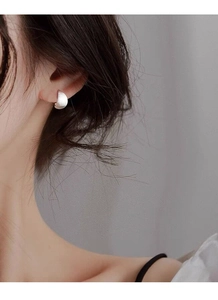 Gros plan d'une boucle d'oreille incurvée en argent S999 avec texture métal brossé mat