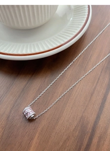 Macro shot of S925 silver necklace with pink square zircon pendant on wooden surface