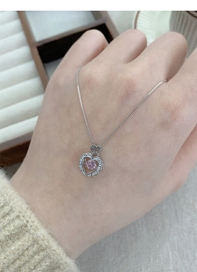 Detail of S925 sterling silver heart necklace with pink stone on hand model